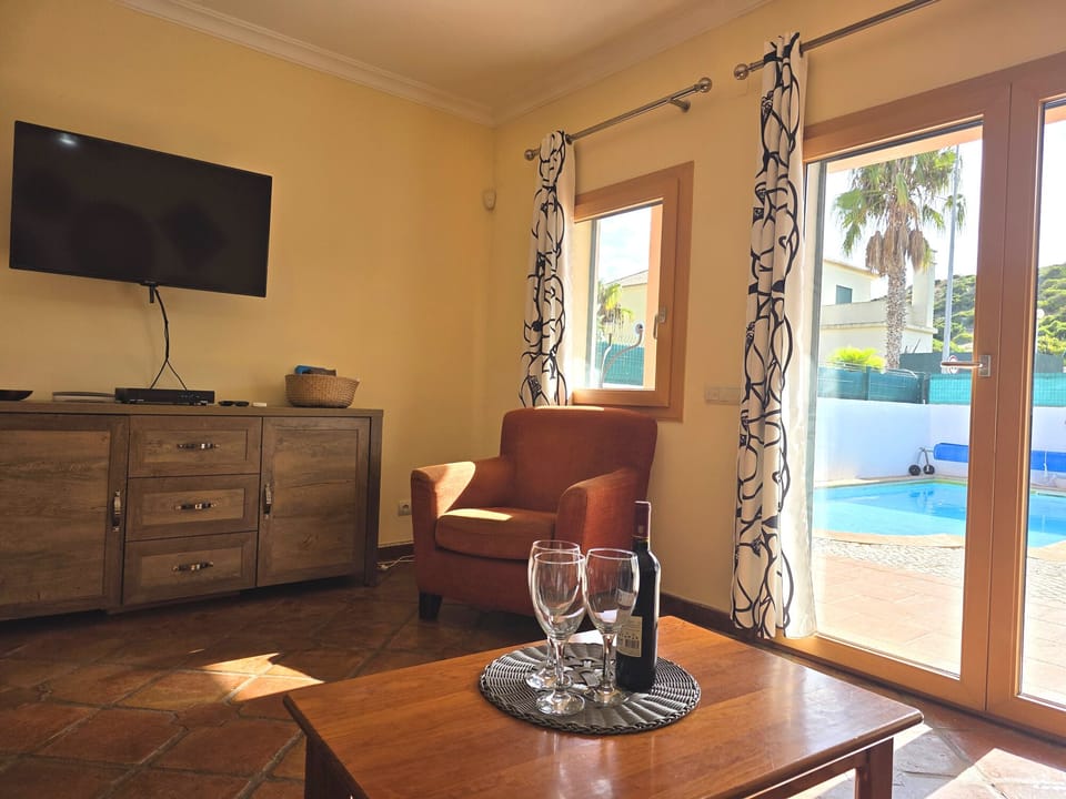 Bright lounge/diner has wall mounted TV and doors to the pool patio