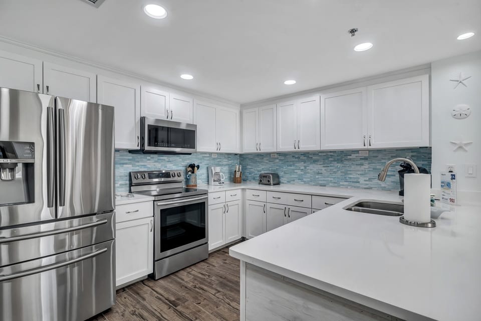This fully functional kitchen boasts stainless steel appliances, sleek countertops, a decorative backsplash, and ample cabinet storage, ideal for everyday cooking and entertaining.