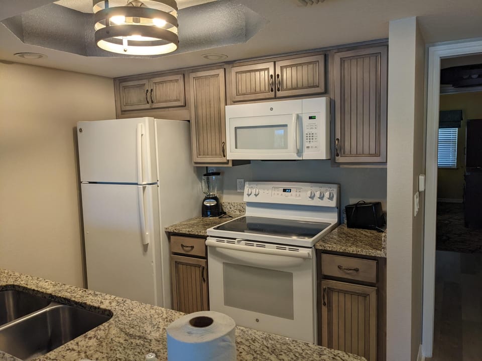 View of Kitchen. Full size stove and refrigerator, toaster, and blender.