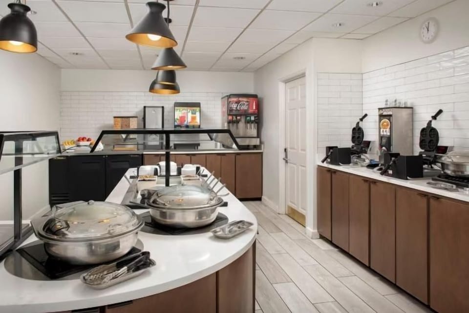 Hot breakfast buffet station with chafing dishes, waffle irons, and a Coca-Cola dispenser