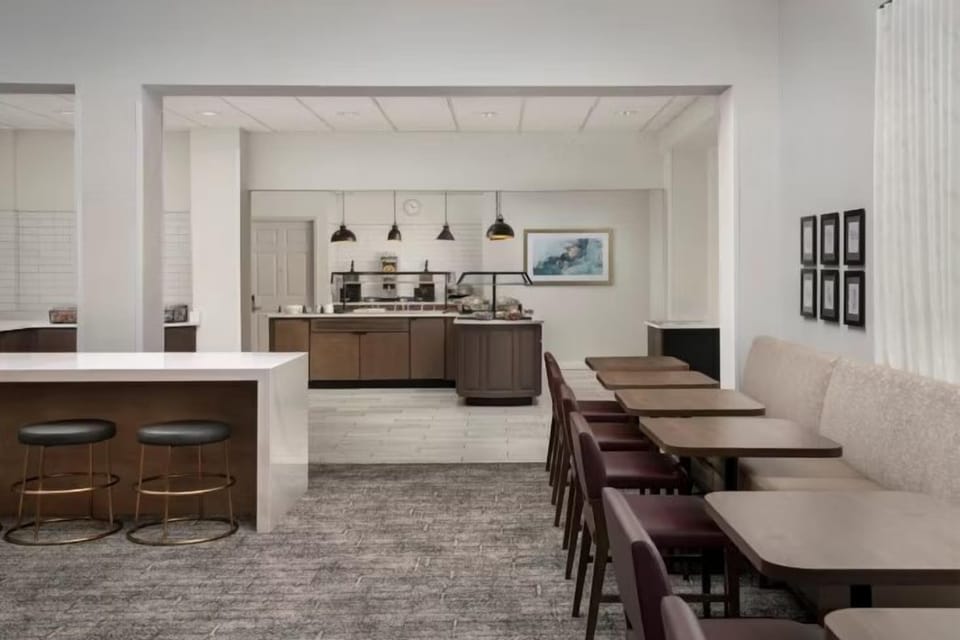 Dining area with maroon-upholstered chairs, tan booth seating, and a service counter at the rear