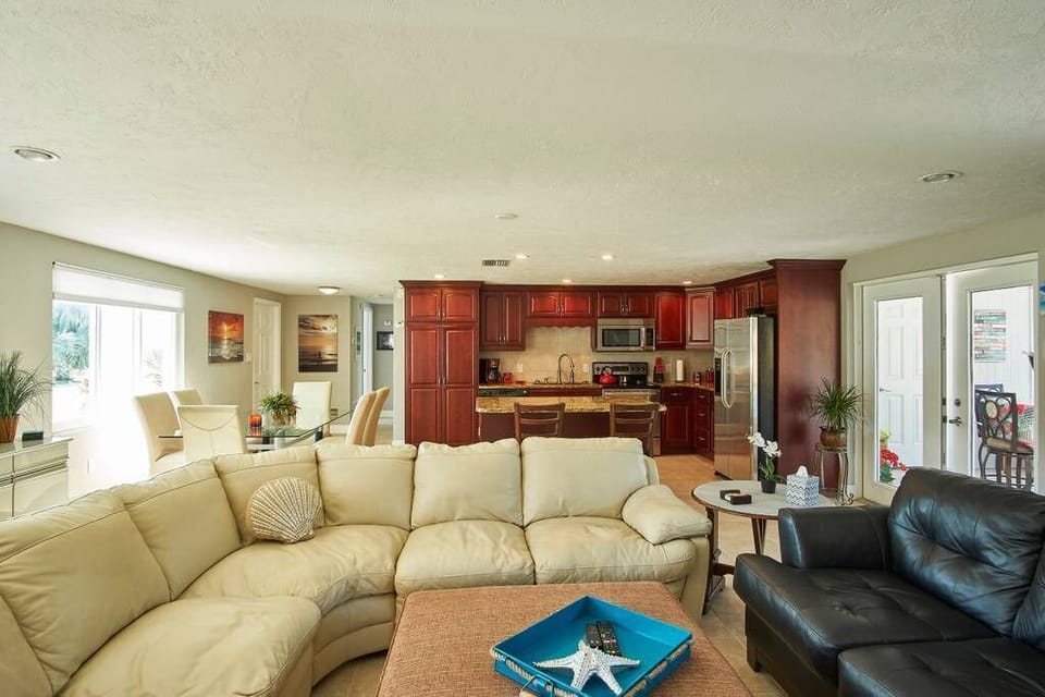 Kitchen opens to living area with leather sofas, 65" smart TV & LED fireplace.
