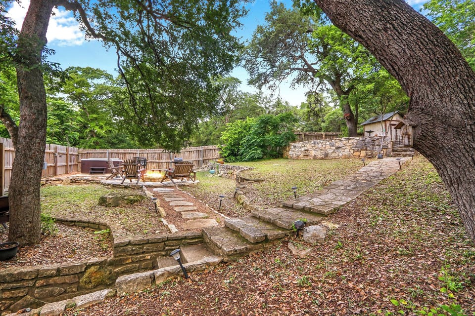 Steps lead up from the back door to the terraced yard.  On the lower terrace is the path to the fire pit and hot tub.