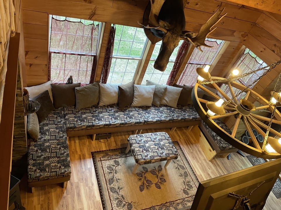 Looking down from open loft to livingroom large couch seats many.