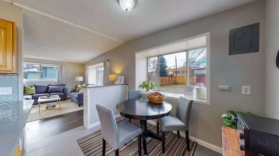 Bright dining area with a round table, cozy seating, and a large window overlooking the backyard.