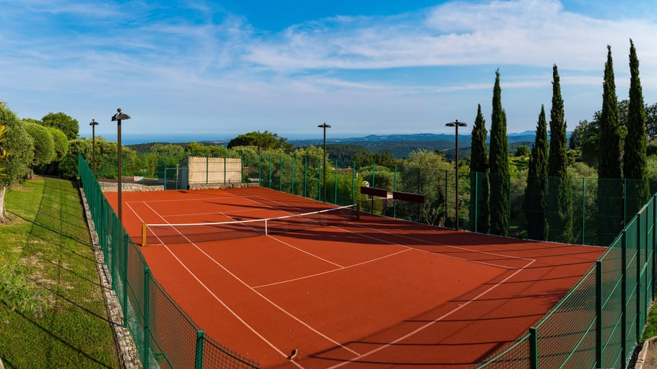 Floodlit tennis court with artificial clay surface. 