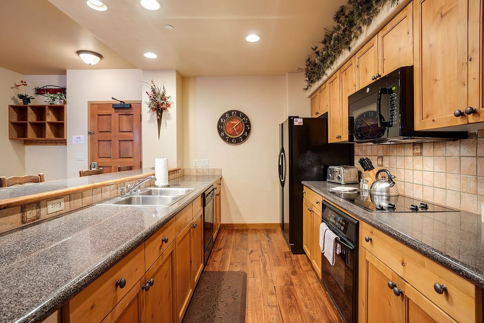 Your spacious kitchen awaits with warm wood cabinetry, granite counters, and everything needed to create memorable meals during your stay.