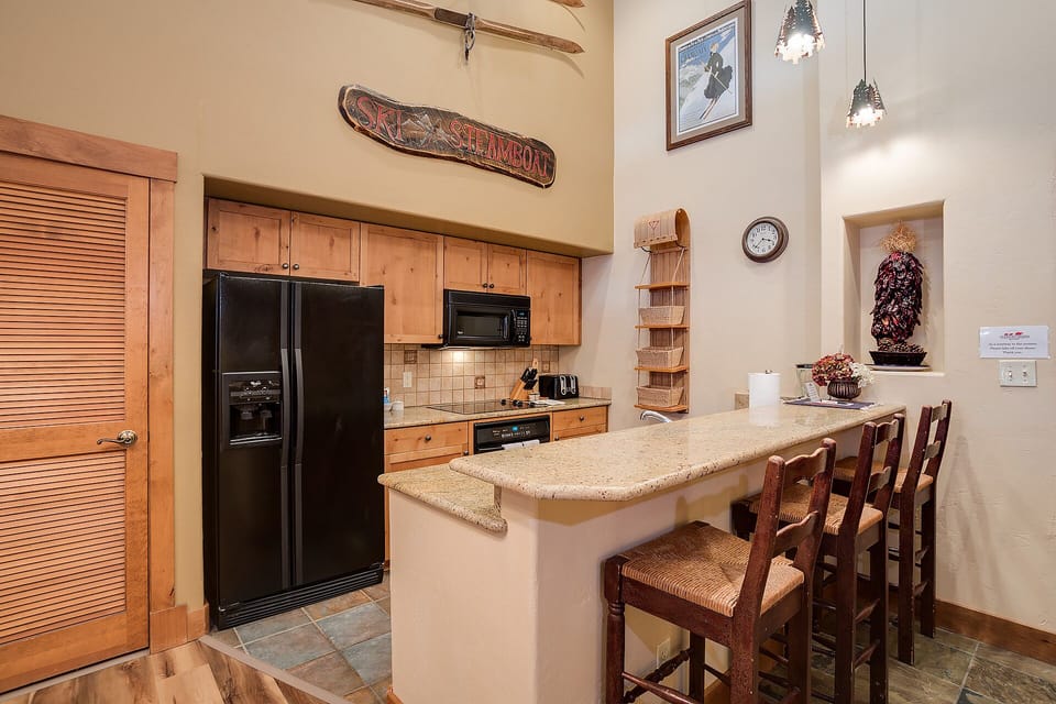 Your fully equipped kitchen features warm wood cabinets, granite counters, and a breakfast bar perfect for morning coffee or casual meals.