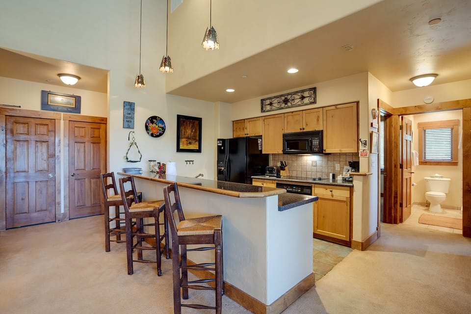 Your spacious open-concept kitchen welcomes you with warm wood cabinetry, granite counters, and a breakfast bar perfect for morning coffee.
