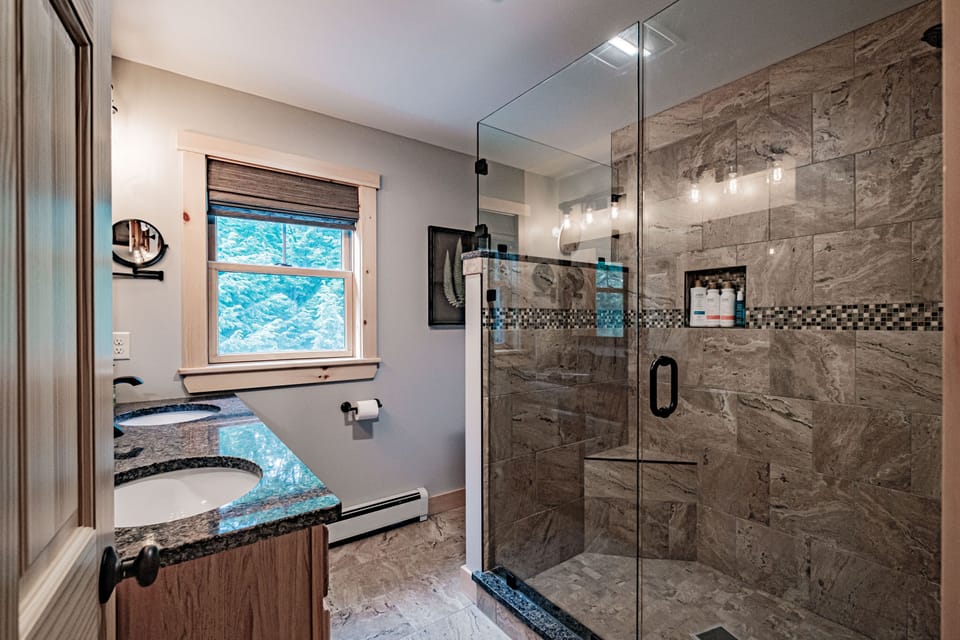 En suite bathroom has spacious tiled shower with glass enclosure