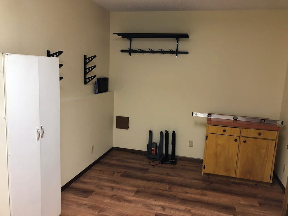 Storage room with racks for skis and snowboards, boot driers, and workbench