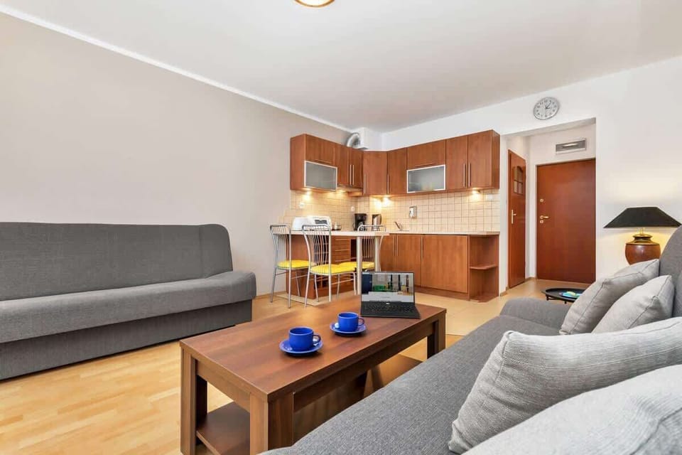 A bright living room with a grey sofa, wooden coffee table, and large windows that fill the space with natural light.