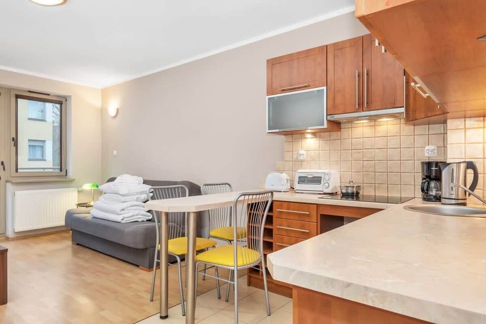 A spacious kitchen with light wooden cabinets, tiled backsplash, and modern appliances including a microwave and stovetop. A small dining area is situated near the entrance, providing a casual spot for meals.