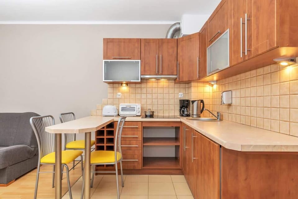 This image focuses on the kitchen and dining space, with a dining table that seats two people. The well-lit area showcases polished wooden cabinetry and practical kitchen amenities.
