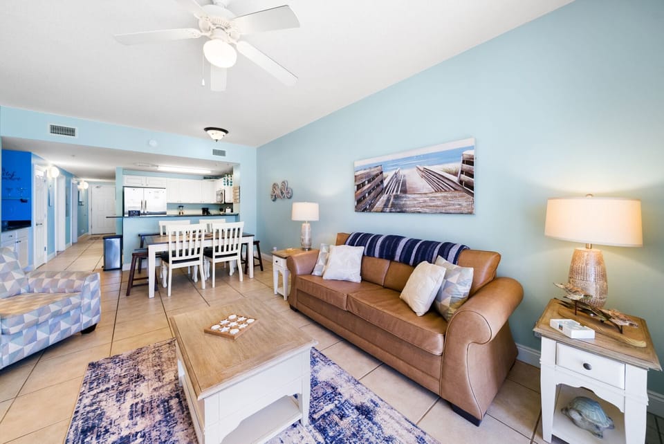 Relax in your bright, open living space with leather sofa, coastal decor, and fully equipped kitchen perfect for memorable beach getaways.