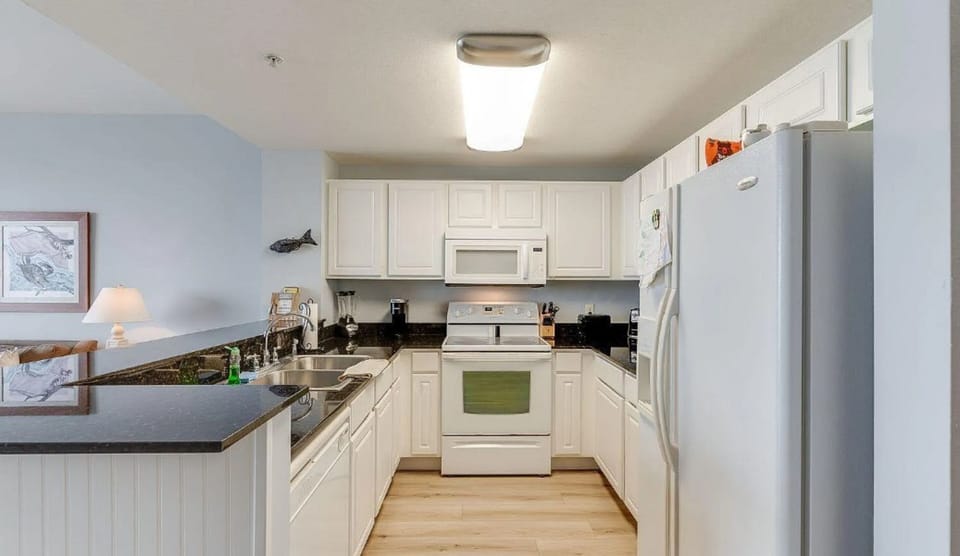 Step into your fully equipped kitchen with granite countertops, white cabinetry, and modern appliances ready for your culinary adventures.
