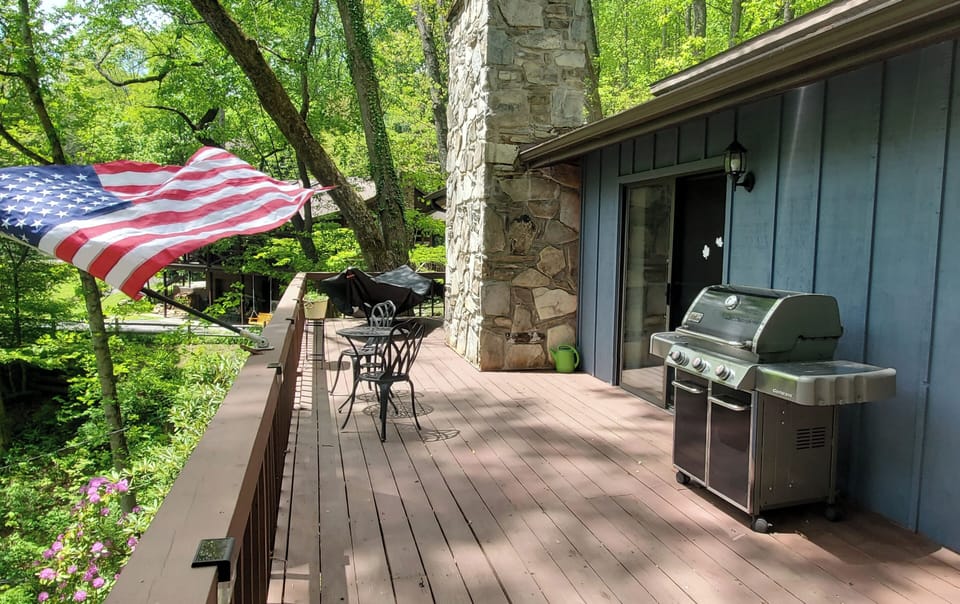 Spacious wraparound deck with grill, outdoor dining, and peaceful mountain surroundings.