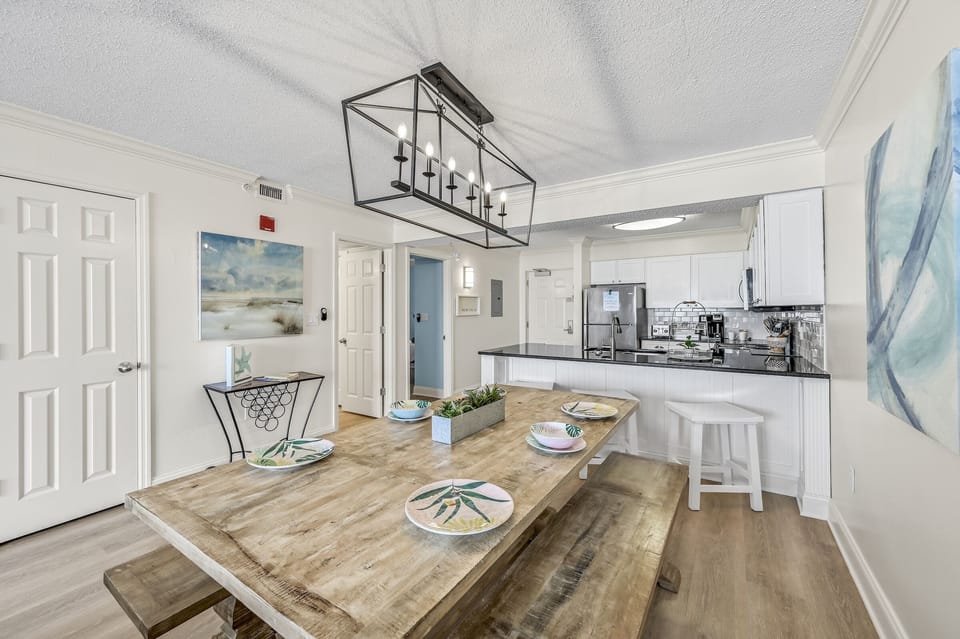 Your bright open kitchen and dining space features coastal artwork and a rustic farmhouse table where memorable meals await.