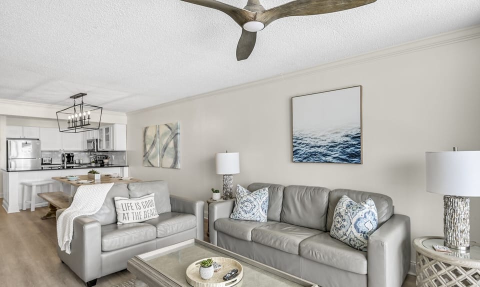 Sink into plush gray sofas in your bright, coastal-styled living space where ocean art sets the perfect beachy mood.
