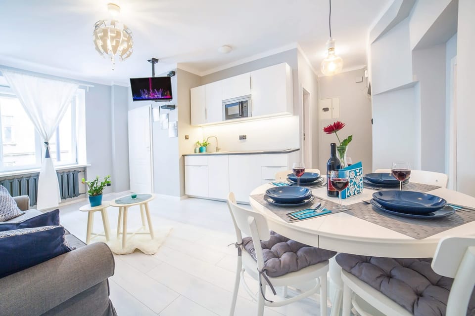 Living room with a sofa bed, TV and kitchenette with dining area.