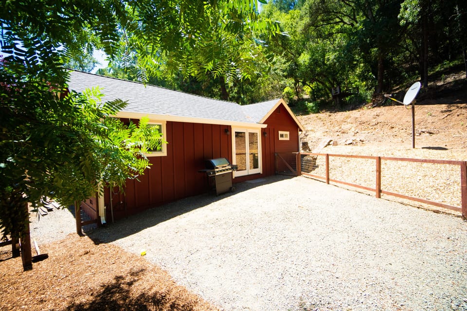 Fenced in back yard, with dog house and BBQ.