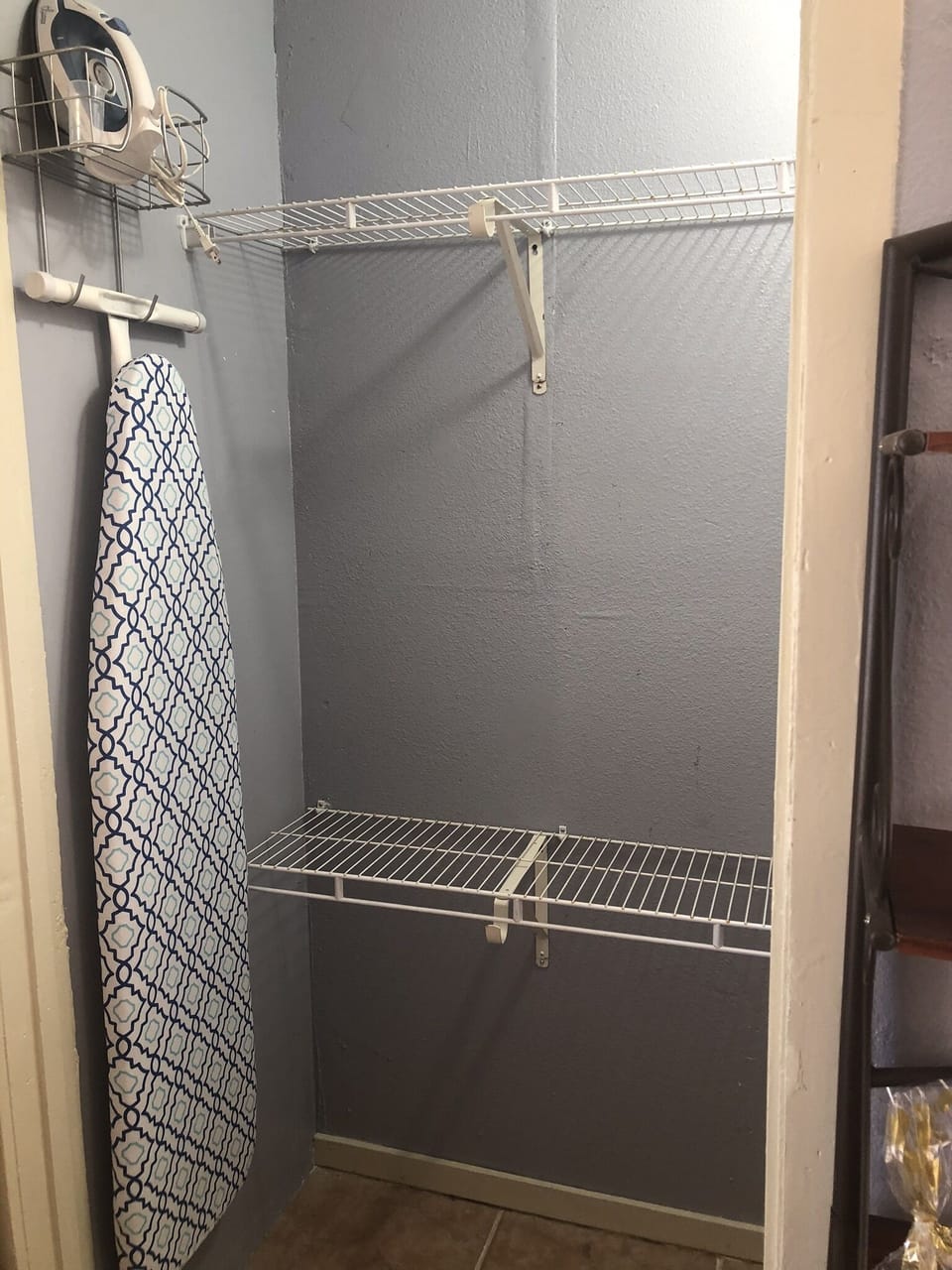 Closet for clothes, ironing board, and iron. 