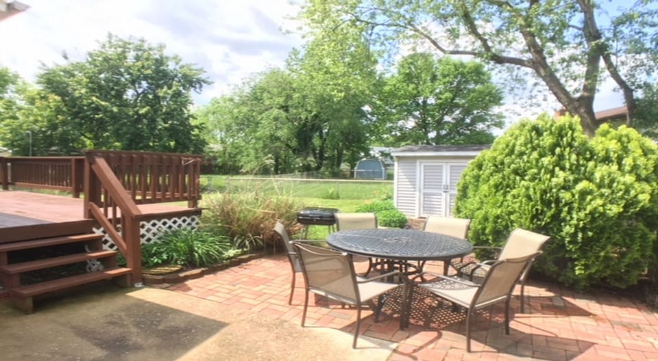 Brick patio a charcoal grill, a table and chairs.