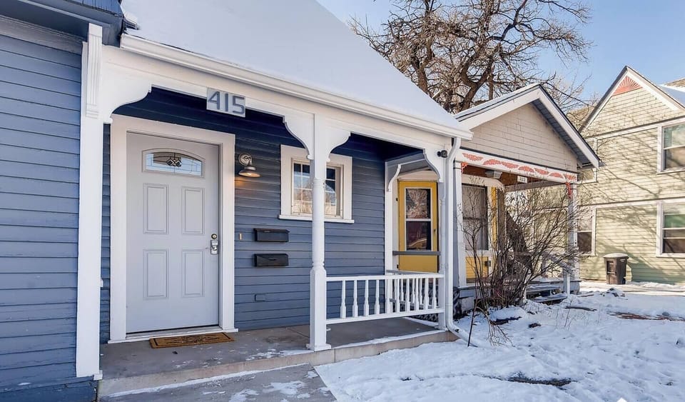 Charming front entry at 415 with a covered porch, fresh paint, and snowy path leading to the welcoming doorway.

