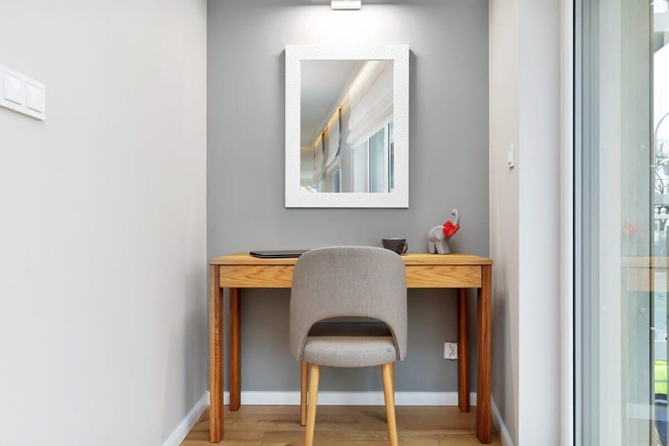 This image focuses on a writing desk with a chair and a decorative mirror above it. The setup is perfect for work or study.
