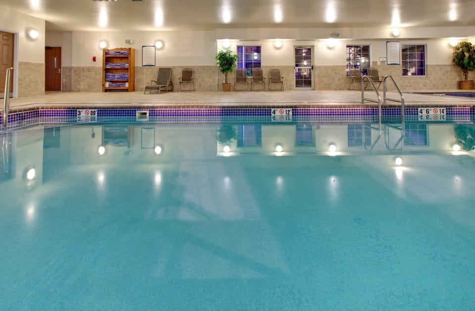 Spacious indoor swimming pool with bright reflections from overhead lights.