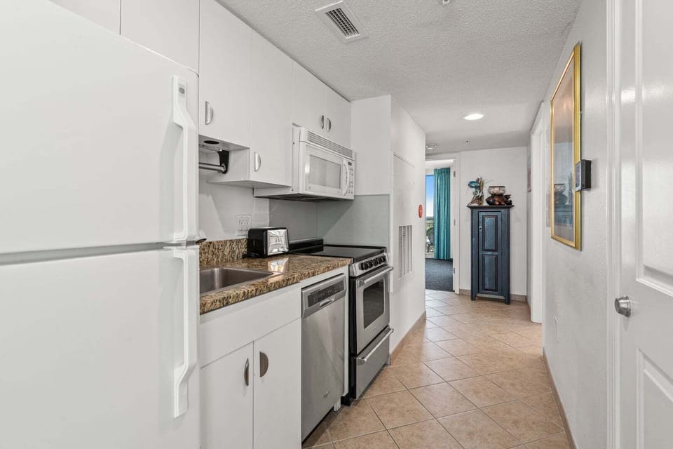 Kitchen with white cabinetry, a full-size oven and microwave at Avista Ocean Resort 1514, Ocean Drive vacation rental