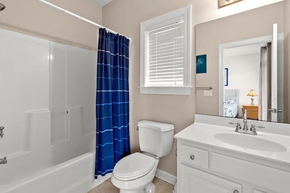 Vanity, mirror and a blue shower curtain in a bathroom at Palmetto Coast, Villa B, Crescent Beach