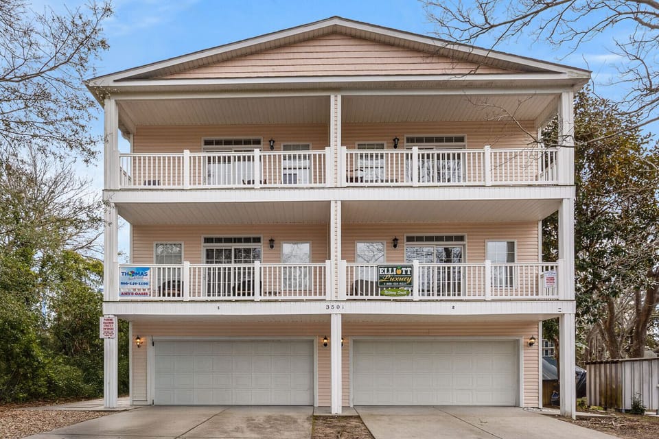 Peach-sided beach house with white railings and balconies at Amy's Oasis, a 5-bedroom Windy Hill vacation rental