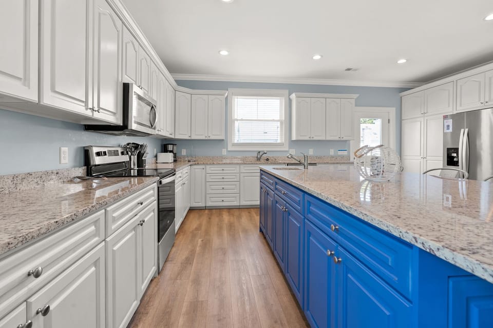Kitchen with white cabinetry and a window above the sink at Cole's Gold, a 5-bedroom Crescent Beach rental