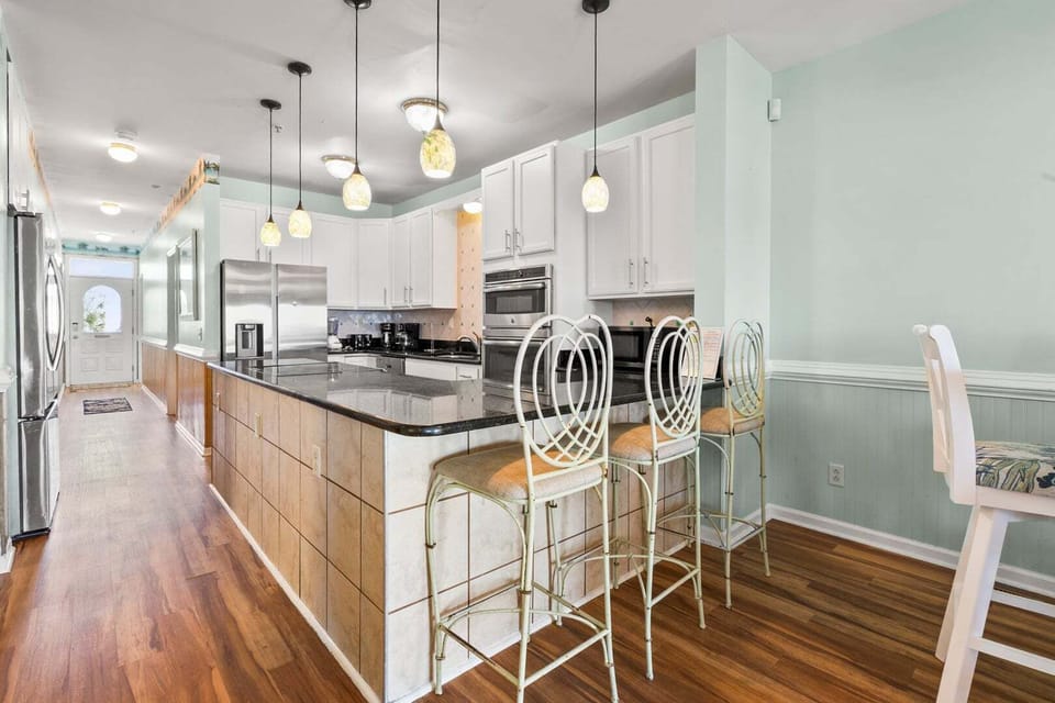 Kitchen island with bar stools and white cabinetry at Diamond Dunes B, a Crescent Beach vacation rental