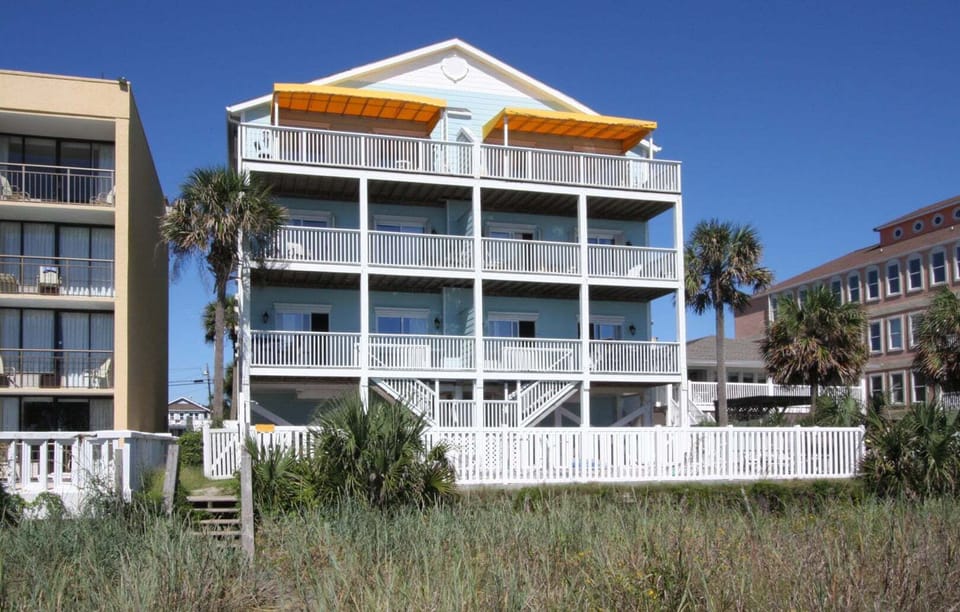 Oceanfront exterior with yellow awnings and porch stairs at Diamond Dunes B, an 8-bedroom Crescent Beach rental
