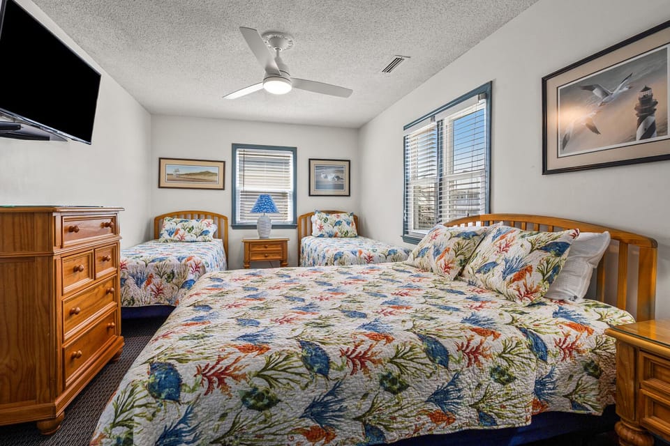 Bedroom with three beds, a wall TV and a dresser at Roberts House, South Villa, Cherry Grove