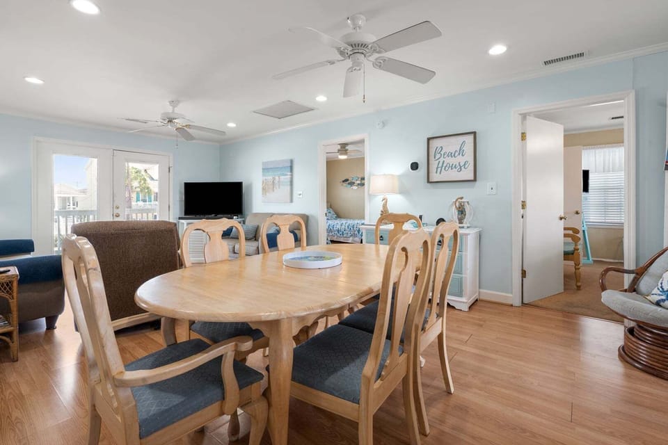 Round dining table and six chairs under a ceiling fan at Anchor in the Waves, a Cherry Grove vacation rental