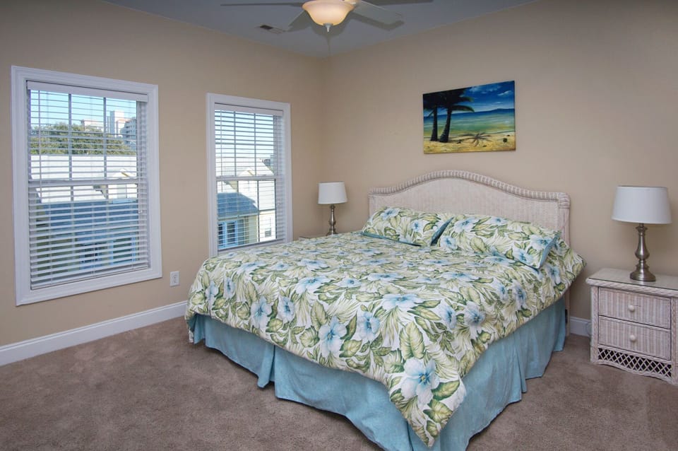 Floral bedding and shuttered windows in a bedroom at West Winds II, Crescent Beach, North Myrtle Beach