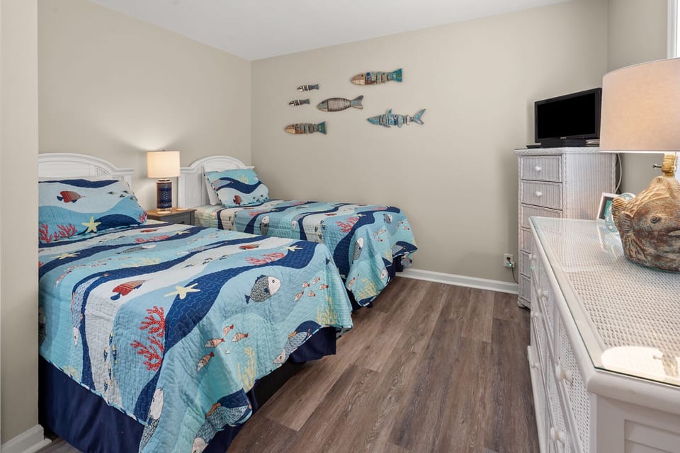 Two beds with coastal bedding and fish wall art at Surf Villas II C2, Ocean Drive, North Myrtle Beach