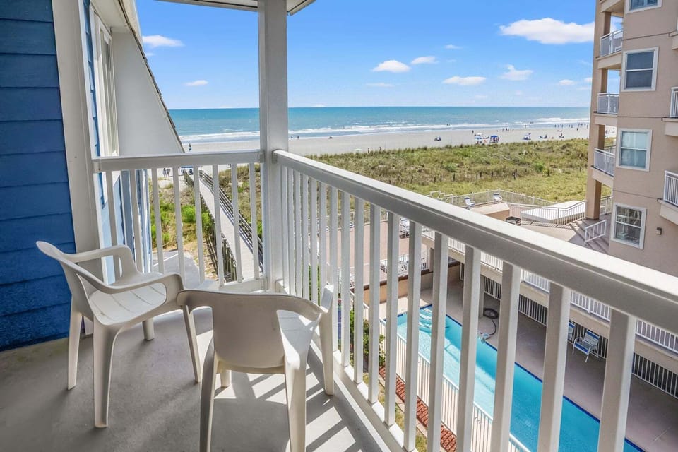Balcony chairs overlooking the pool and beach at Summer Place C3, a 2-bedroom Cherry Grove rental
