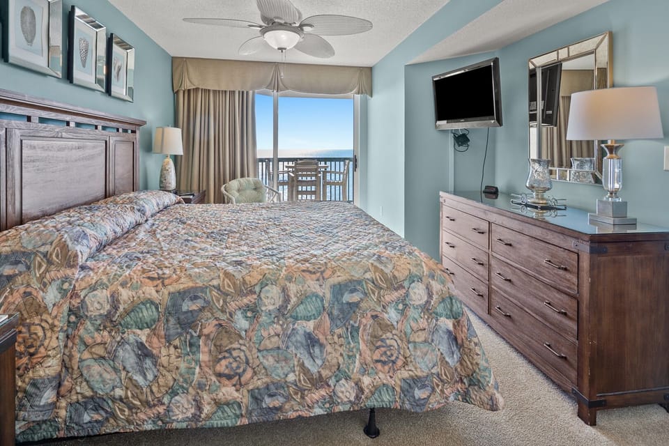 Bedroom with a wall TV and a sliding door to the ocean-view balcony at Ashworth 1103, Ocean Drive