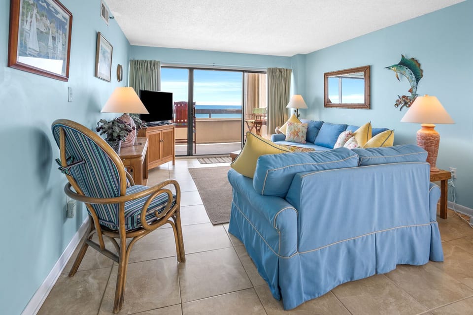 Living room with a blue sofa, striped chair and sliding doors to the ocean at Sea Pointe 708, Cherry Grove