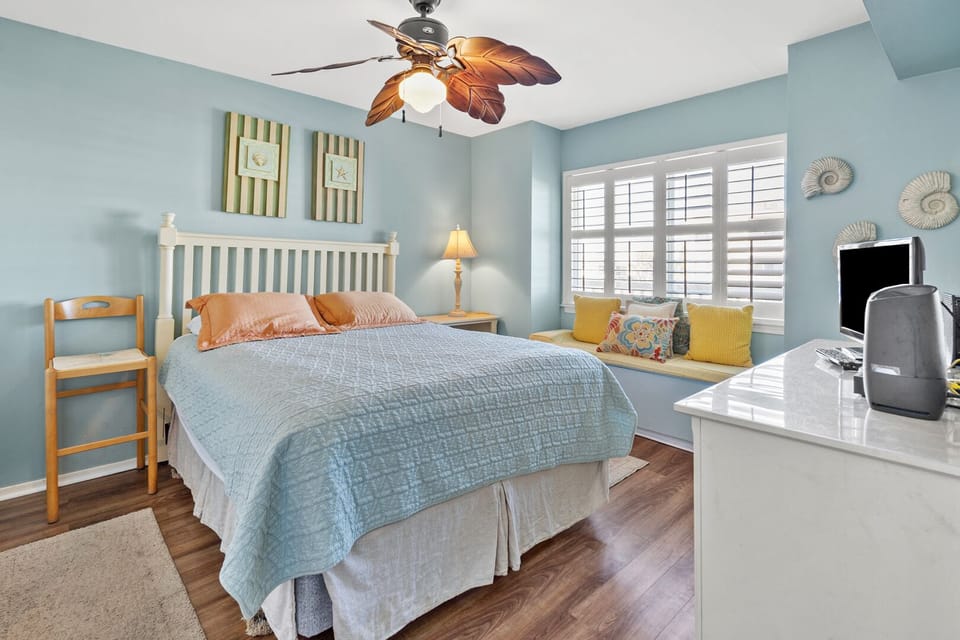 Bedroom with a cushioned window seat and blue quilt at Raintree Villas 1E, Cherry Grove vacation rental