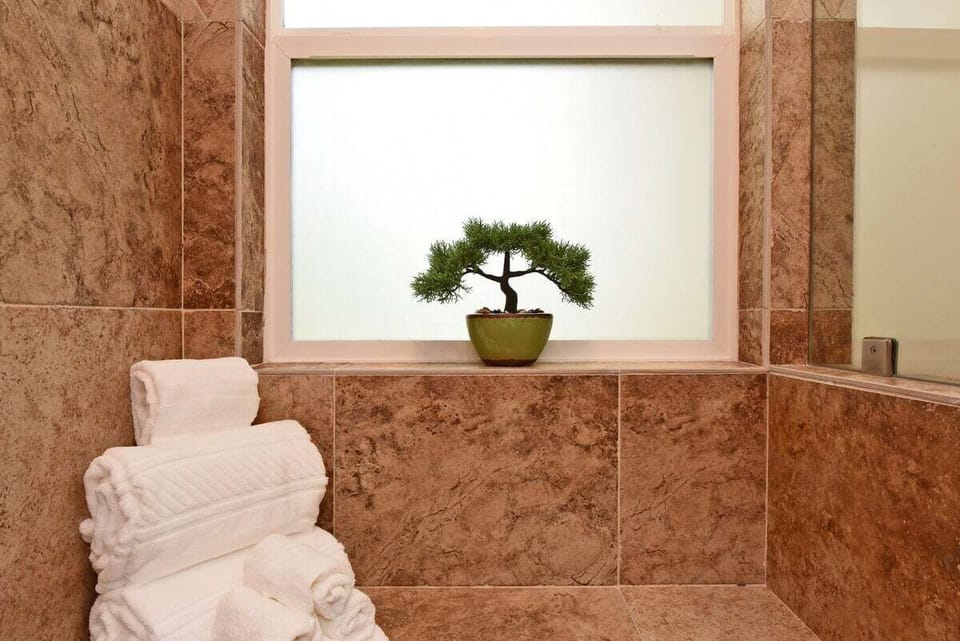 Bright bathroom featuring a large window, towels, and stone surround.
