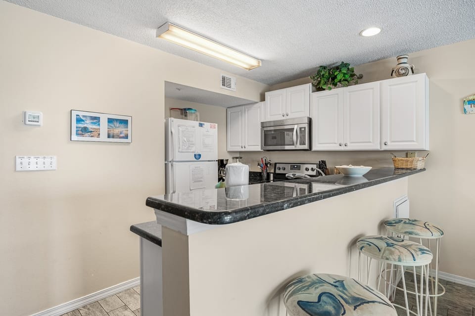 A crisp kitchen with bar seating and full appliances.
