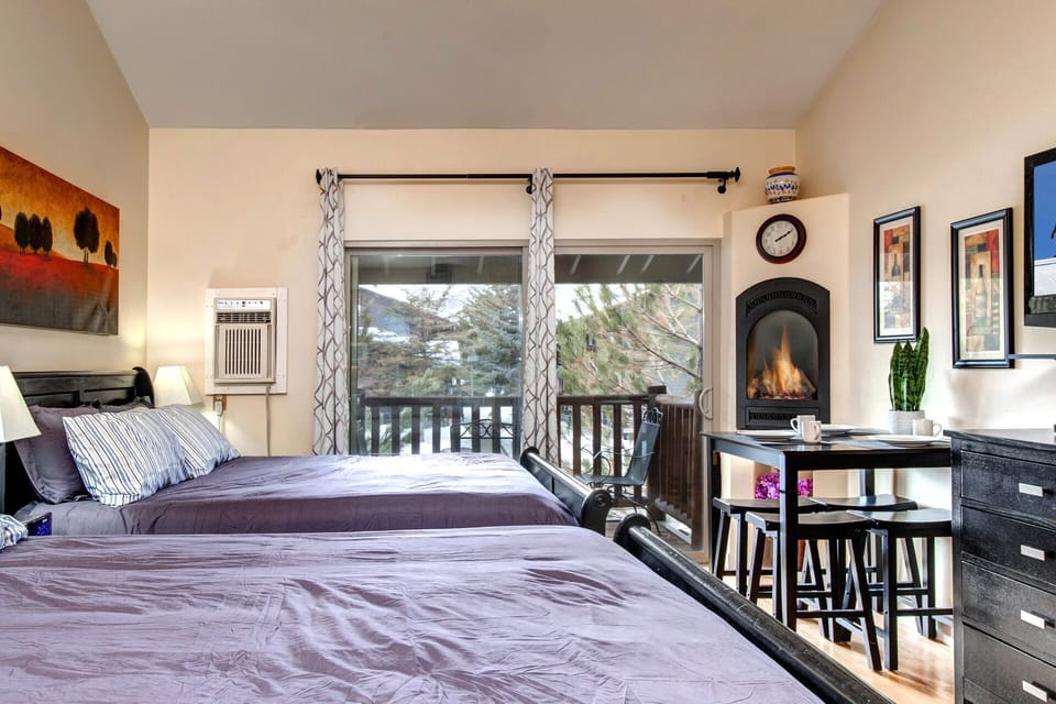 Cozy up in your inviting bedroom with two plush beds, charming fireplace, and mountain-view windows—your perfect retreat after a day of adventure.