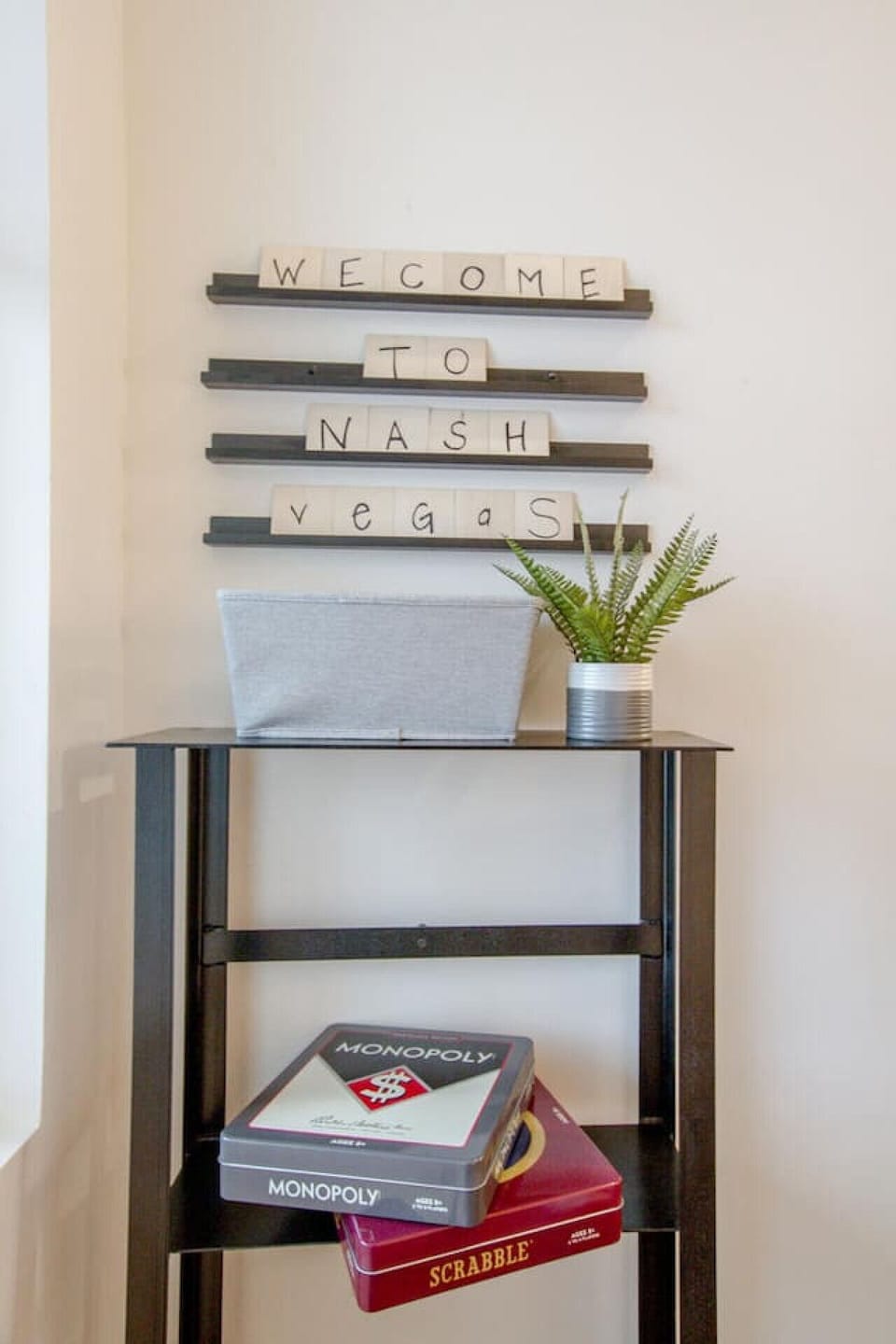Decorative entryway console with To Nash Vegas sign, plant, and coastal accessories