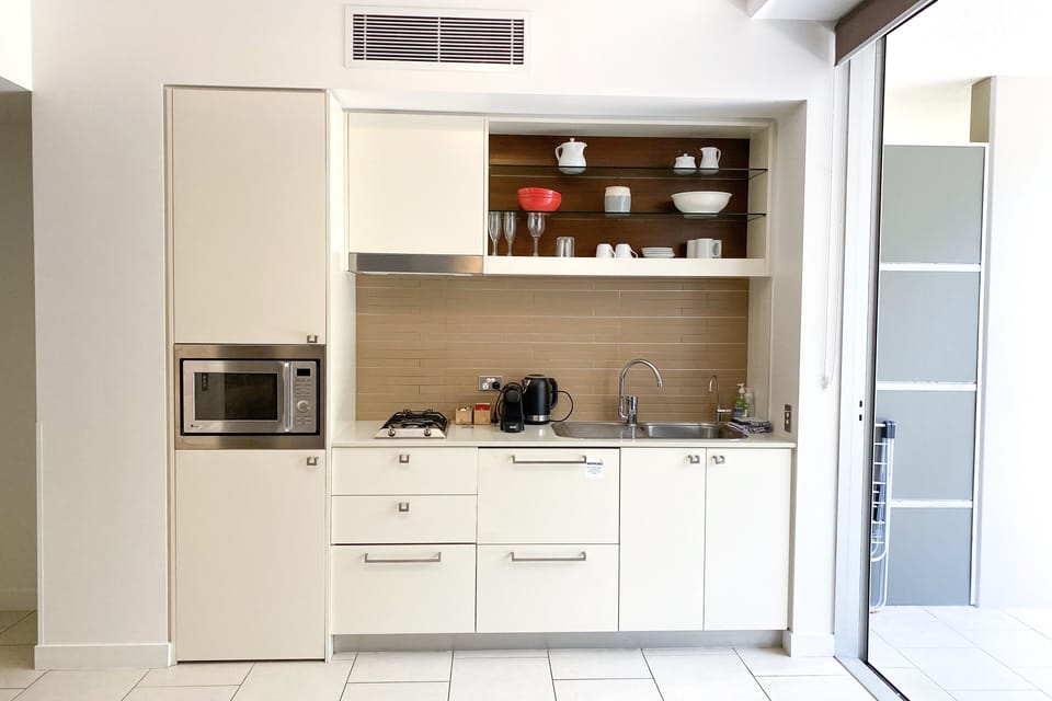 Kitchen area with gas stove, microwave, fridge, and coffee machine.
