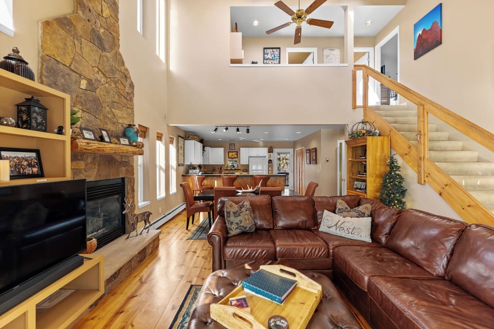 Relax in this warm, open living space with rich leather seating, stone fireplace, and soaring ceilings that create your perfect mountain retreat.